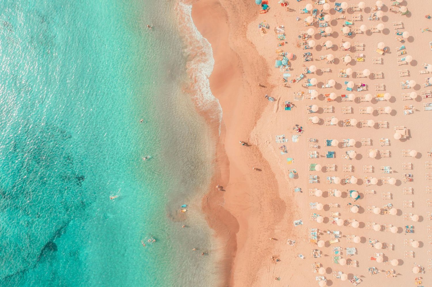 The Gulf Coast shoreline from above, rows of umbrellas on white sand
