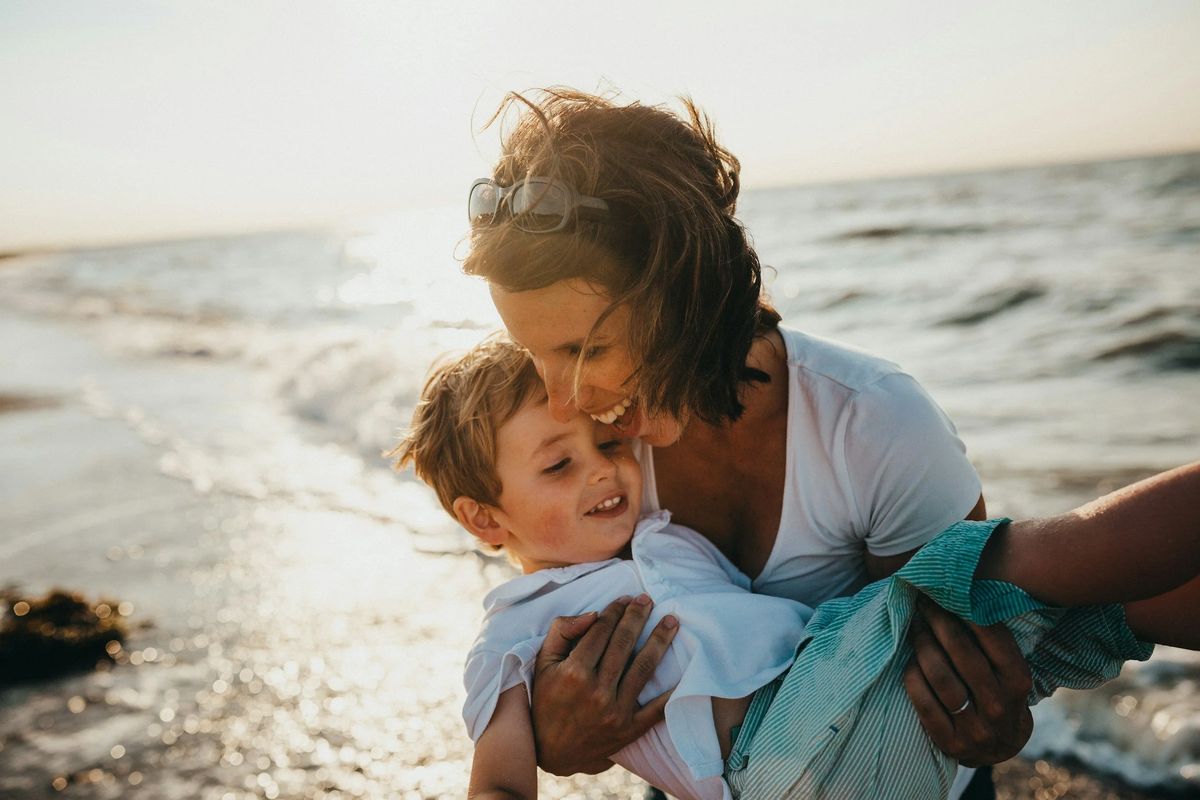 A parent and child playing at the water's edge